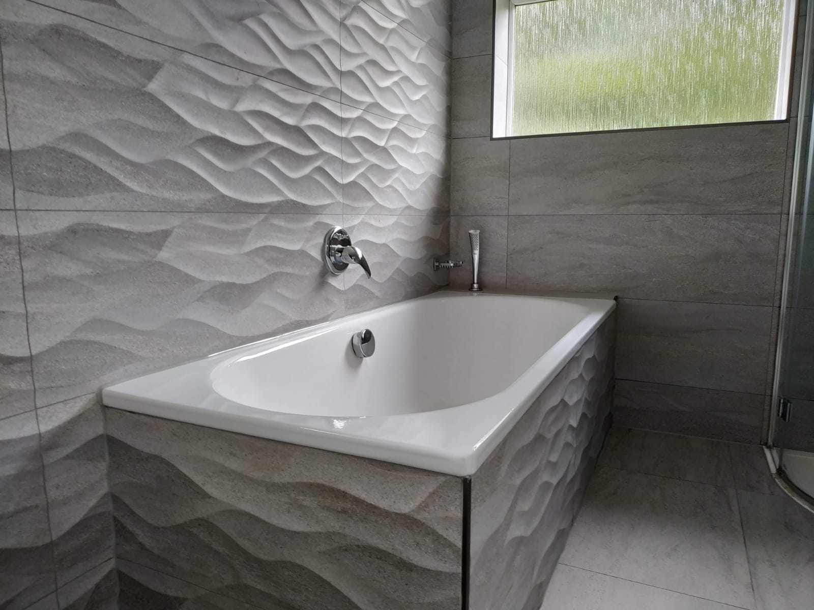 Bathroom with textured wave-pattern tiles around the bath