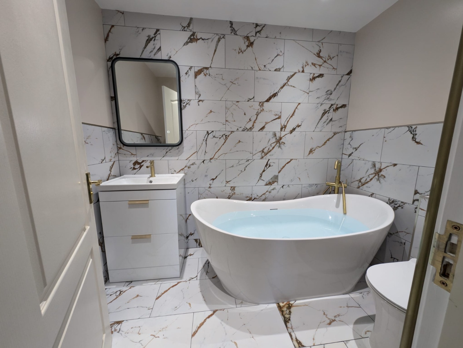 Bathroom with freestanding bath and marble-effect tiling
